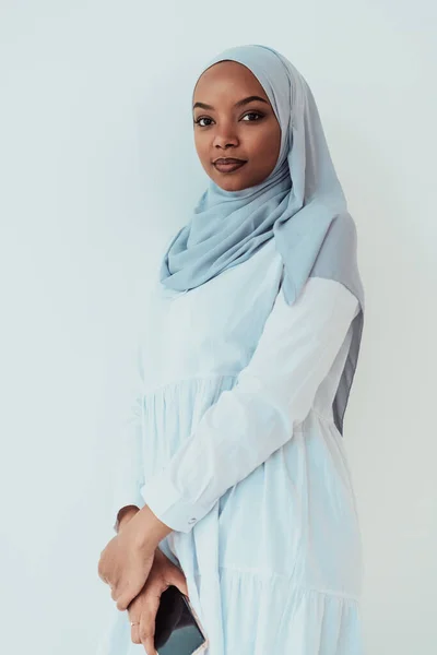Seorang wanita Muslim Afrika menggunakan smartphone pada latar belakang putih — Stok Foto