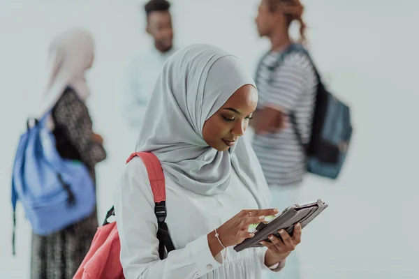 Estudiante africana con un grupo de amigas de fondo vestidas con ropa tradicional islámica de hiyab. Enfoque selectivo —  Fotos de Stock