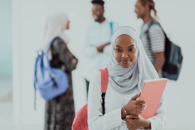 Geleneksel İslami tesettüre bürünmüş bir grup arkadaşı olan Afrikalı bir kız öğrenci. Odaklanma seç 