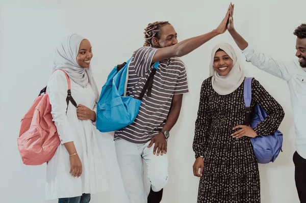 Fénykép egy csapat boldog afrikai diákról, akik beszélgetnek és találkoznak, miközben házi feladatokon dolgoznak, hagyományos szudáni muszlim hidzsábot viselő lányokkal. — Stock Fotó
