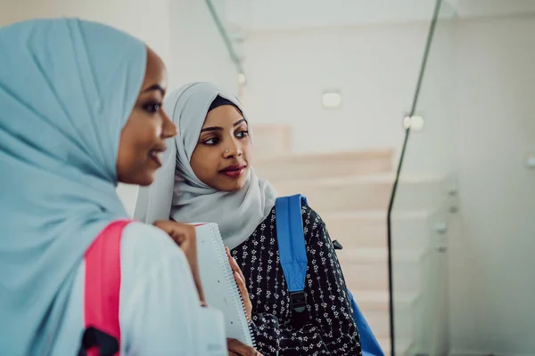 Una foto de dos alumnas musulmanas africanas con una mochila en la espalda en una casa moderna. — Foto de Stock