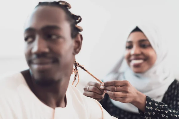 A young Muslim couple has a romantic time at home while the woman makes the hairstyle for her husband female wearing traditional Sudan Islamic hijab clothes. — Stock Photo, Image