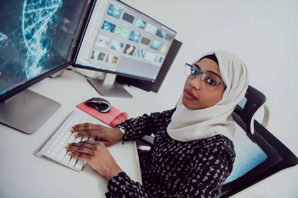 Genç Afro-Amerikalı modern Müslüman iş kadını büyük ekranlı, yaratıcı, parlak bir ofis işyerinde eşarp takıyor.. — Stok fotoğraf