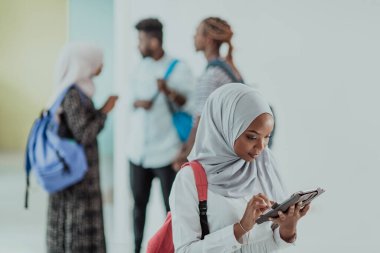 Geleneksel İslami tesettüre bürünmüş bir grup arkadaşı olan Afrikalı bir kız öğrenci. Odaklanma seç 
