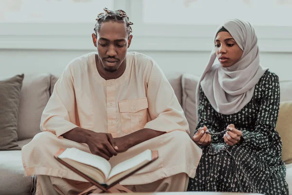 アフリカ人ムスリムカップルに家でラマダーン読書quran holy islam book. — ストック写真