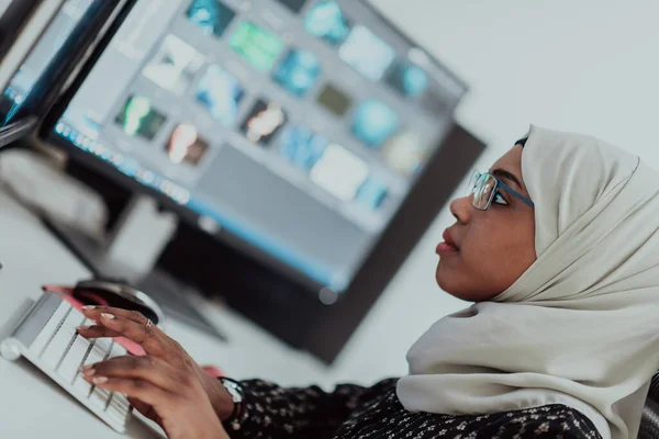 Jeune femme d'affaires musulmane moderne afro-américaine portant un foulard dans un bureau lumineux créatif avec un grand écran. — Photo