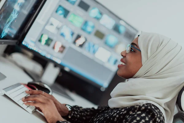 Jeune femme d'affaires musulmane moderne afro-américaine portant un foulard dans un bureau lumineux créatif avec un grand écran. — Photo