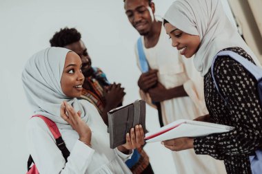 Geleneksel İslami tesettüre bürünmüş bir grup arkadaşı olan Afrikalı bir kız öğrenci. Odaklanma seç 