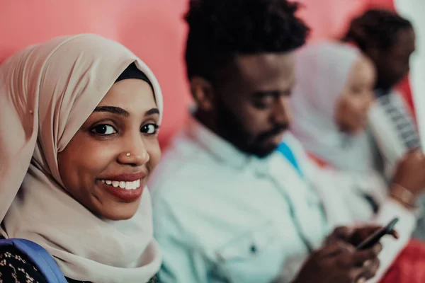 Een groep Afrikaanse moslimstudenten gebruikt smartphones terwijl ze voor een roze achtergrond staan — Stockfoto