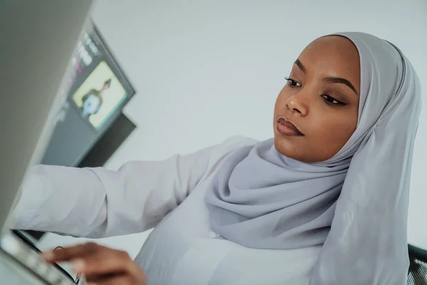 Junge afroamerikanische moderne muslimische Geschäftsfrau mit Kopftuch an einem kreativen, hellen Büroarbeitsplatz mit großer Leinwand. — Stockfoto