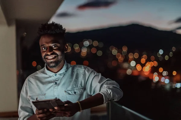 Gece şehir caddesinde genç bir adam arka planda Bokeh ve Neon şehir ışıklarıyla akıllı telefondan mesaj atıyor.. — Stok fotoğraf