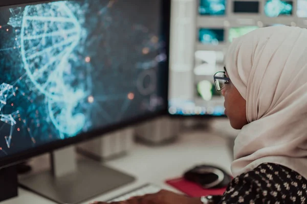 Giovane afro-americana moderna donna d'affari musulmana indossa una sciarpa in un ufficio luminoso creativo sul posto di lavoro con un grande schermo. — Foto Stock