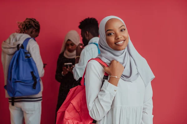 Un grupo de estudiantes musulmanes africanos con mochilas posando sobre un fondo rosa. el concepto de educación escolar. — Foto de Stock