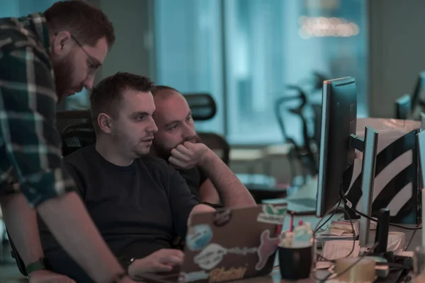 Ein Foto von drei Männern, die in einem modernen Büro gespannt auf einen Computer starren. Selektiver Fokus — Stockfoto