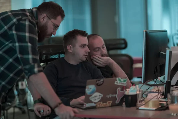 Фото трех мужчин, пристально смотрящих на компьютер, сидящих в современном офисе. Селективный фокус — стоковое фото