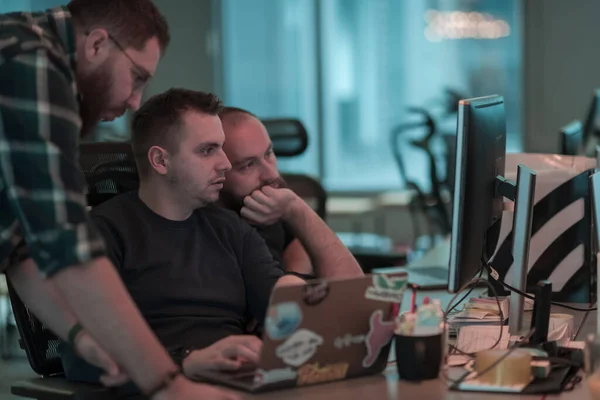 Egy fénykép három férfiról, akik egy számítógépet bámulnak, miközben egy modern irodában ülnek. Szelektív fókusz — Stock Fotó