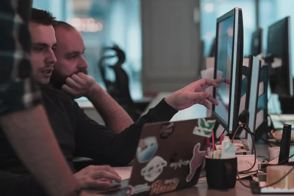 Et bilde av tre menn som stirrer på en datamaskin mens de sitter på et moderne kontor. Selektivt fokus – stockfoto