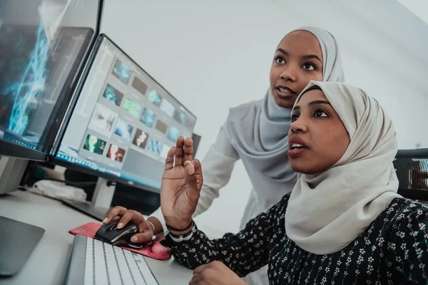 Friends at the office two young Afro American modern Muslim businesswomen wearing scarf in creative bright office workplace with a big screen — Stock Photo, Image