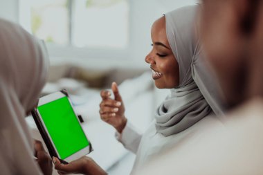 Bir grup mutlu Afrikalı öğrenci sohbet ediyor ve takım buluşması yapıyor. Ev ödevi için birlikte çalışıyorlar. Geleneksel Müslüman başörtüsü giyen kızlar.