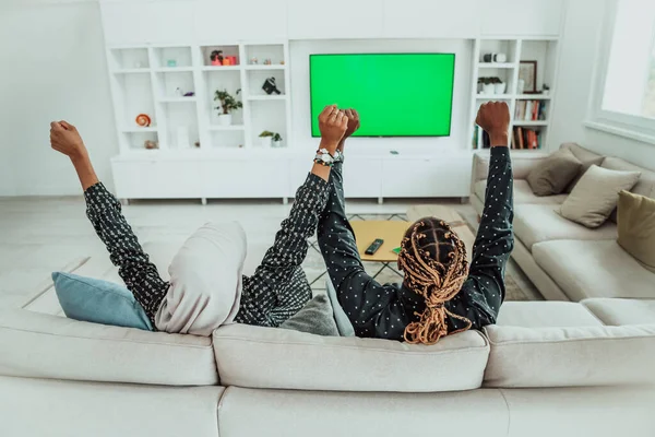 Couple africain assis sur le canapé Regarder la télévision ensemble Chroma Green Screen Femme portant des vêtements Hijab islamique — Photo