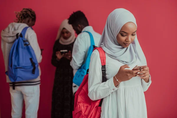 Un grupo de estudiantes musulmanes africanos con mochilas posando sobre un fondo rosa. el concepto de educación escolar. — Foto de Stock