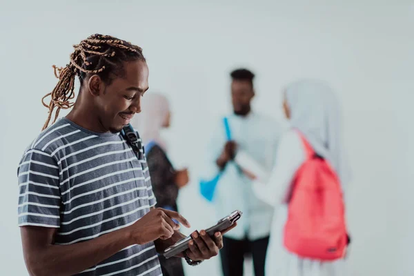 Univerzitní životní styl pohledný mladý africký student muž drží tablet počítače a usmívá se, zatímco stojí proti univerzitě se svými přáteli mají tým setkání v pozadí. Vysoce kvalitní — Stock fotografie