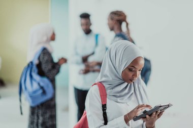 Geleneksel İslami tesettüre bürünmüş bir grup arkadaşı olan Afrikalı bir kız öğrenci. Odaklanma seç 