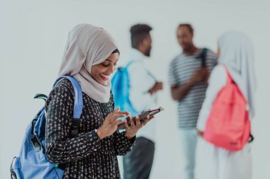 Geleneksel İslami tesettüre bürünmüş bir grup arkadaşı olan Afrikalı bir kız öğrenci. Odaklanma seç 