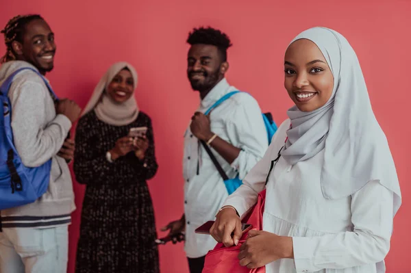 En grupp afrikanska muslimska studenter med ryggsäckar som poserar på en rosa bakgrund. begreppet skolutbildning,. — Stockfoto