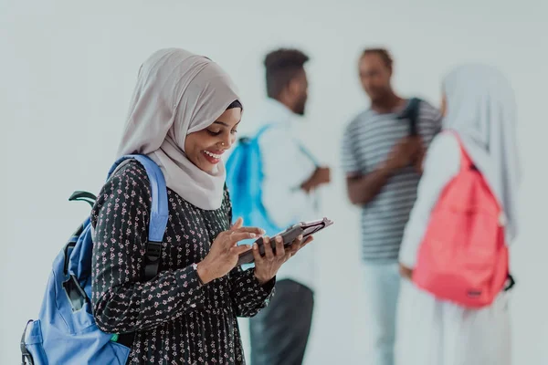 Afrikaanse studente met een groep vrienden op de achtergrond in traditionele islamitische hijab kleding. Selectieve focus — Stockfoto