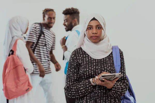 Afrikaanse studente met een groep vrienden op de achtergrond in traditionele islamitische hijab kleding. Selectieve focus — Stockfoto