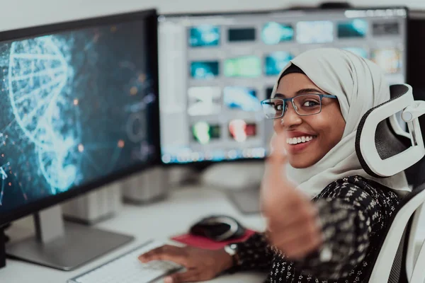 Young Afro-American modern Muslim businesswoman wearing a scarf in a creative bright office workplace with a big screen.