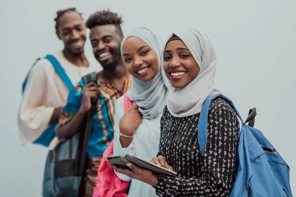Foto de un grupo de estudiantes africanos felices conversando y reuniéndose juntos trabajando en las niñas de la tarea usando el tradicional hiyab musulmán sudanés —  Fotos de Stock