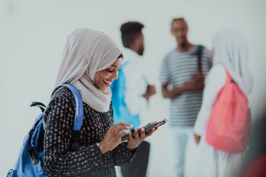 Geleneksel İslami tesettüre bürünmüş bir grup arkadaşı olan Afrikalı bir kız öğrenci. Odaklanma seç 