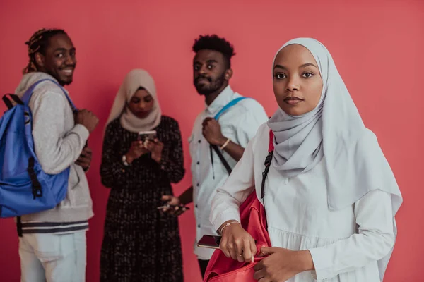 En grupp afrikanska muslimska studenter med ryggsäckar som poserar på en rosa bakgrund. begreppet skolutbildning,. — Stockfoto