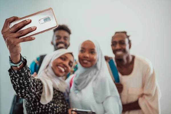 En grupp multietniska studenter tar en selfie med en smartphone på en vit bakgrund. Selektiv inriktning Stockbild