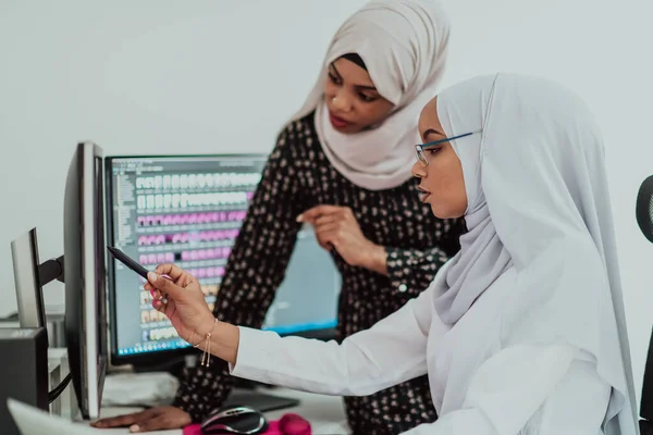 オフィスの友人2人の若いアフリカ系アメリカ人現代イスラム教徒のビジネス女性が大きな画面で創造的な明るいオフィスの職場でスカーフを着て — ストック写真