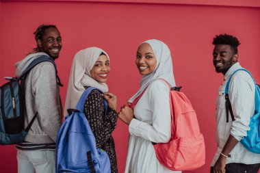 Sırt çantalı, pembe arka planda poz veren bir grup Afrikalı Müslüman öğrenci. Okul eğitimi kavramı.