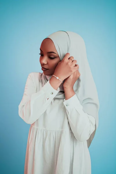Ritratto di giovane moderna bellezza musulmana afro che indossa abiti islamici tradizionali su sfondo blu. Focus selettivo — Foto Stock