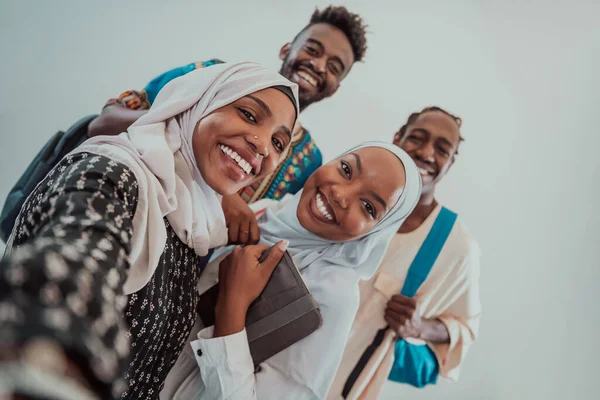Sekelompok siswa multietnis mengambil selfie dengan smartphone pada latar belakang putih. Fokus selektif — Stok Foto