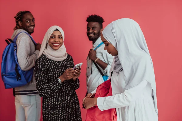 Sekelompok siswa Muslim Afrika dengan ransel berpose pada latar belakang merah muda. konsep pendidikan sekolah. — Stok Foto