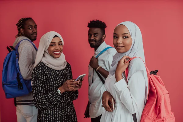 Um grupo de estudantes muçulmanos africanos com mochilas posando em um fundo rosa. o conceito de educação escolar. — Fotografia de Stock