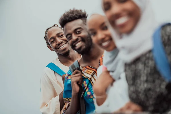 Foto de un grupo de estudiantes africanos felices conversando y reuniéndose juntos trabajando en las niñas de la tarea usando el tradicional hiyab musulmán sudanés —  Fotos de Stock