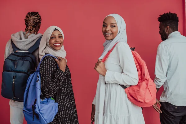 En grupp afrikanska muslimska studenter med ryggsäckar som poserar på en rosa bakgrund. begreppet skolutbildning,. — Stockfoto