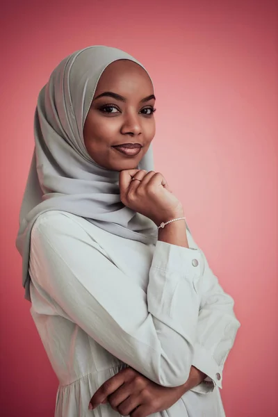 Potret muda muslim muda cantik afro mengenakan pakaian islamik tradisional di latar belakang plastik merah muda. Fokus selektif — Stok Foto