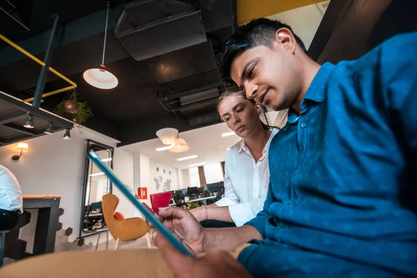 Мультиэтнические бизнесмены мужчина с женщиной коллегой работают вместе за планшетным компьютером в зоне отдыха современного стартап-офиса — стоковое фото