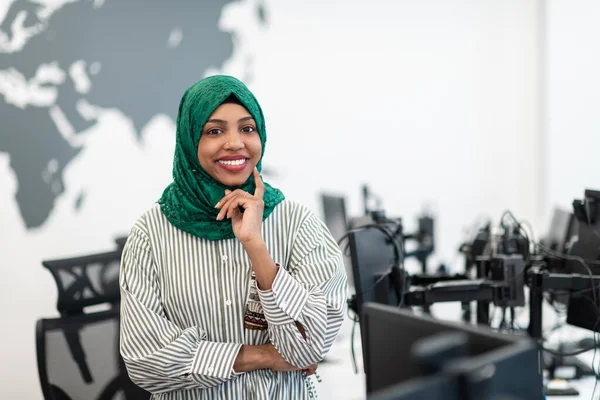 現代のオープンプランスタートアップオフィスに立って緑のヒジャーブとイスラム教徒の黒人女性ソフトウェア開発者の肖像。選択的焦点 — ストック写真
