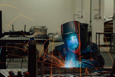 Professional Heavy Industry Welder Working Inside factory, Wears Helmet and Starts Welding. Selective Focus