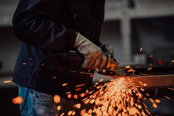 Těžký průmysl Engineering Factory interiér s průmyslovým pracovníkem pomocí úhlové brusky a řezání kovové trubky. Dodavatel v bezpečnostních uniformách a kovových konstrukcích na výrobu tvrdých klobouků. — Stock fotografie