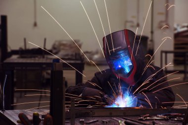 Professional Heavy Industry Welder Working Inside factory, Wears Helmet and Starts Welding. Selective Focus